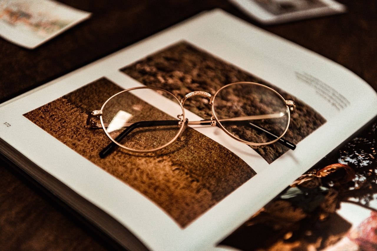 The Art of Drawing Readers In: Your attractive post title goes here Close-up of vintage eyeglasses resting on an open magazine with photos.